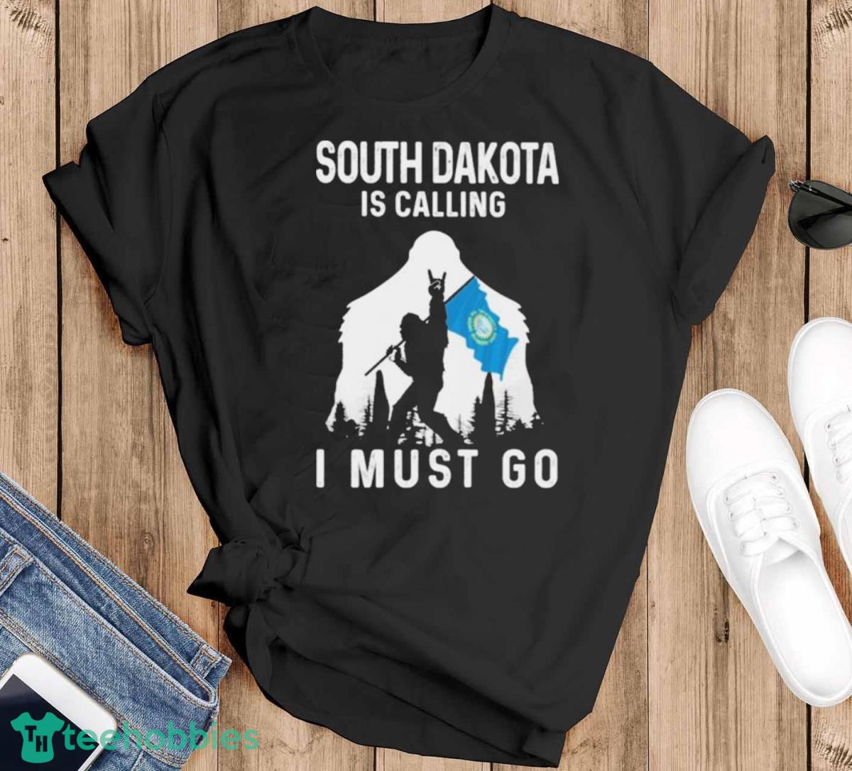 South Dakota Is Calling I Must Go Bigfoot Flag Shirt - Black T-Shirt